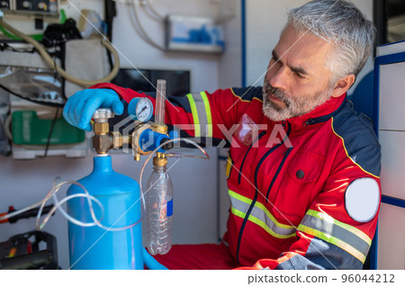 Focused ambulance physician using the oxygenation equipment Focused ambulance physician using the oxygenation equipment 96044212