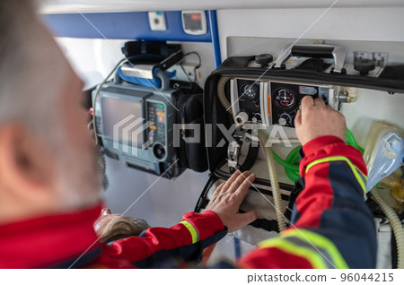 Experienced paramedic preparing a sick person for oxygenation Experienced paramedic preparing a sick person for oxygenation 96044215