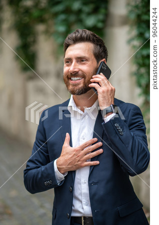 Good-looking young man talking on the phone and looking excited Good-looking young man talking on the phone and looking excited 96044244