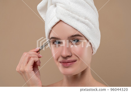 Pretty young girl pluckinh her eyebrows 96044320