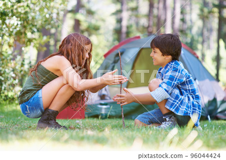 Let me show you.... A young brother and sister starting a campfire. Let me show you.... A young brother and sister starting a campfire. 96044424