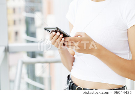 Close up front view young woman holding smartphone, typing message, chatting with friends in social networks. Close up front view young woman holding smartphone, typing message, chatting with friends in social networks. 96044425