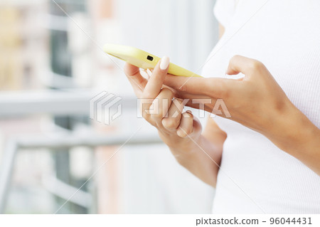 Close up front view young woman holding smartphone, typing message, chatting with friends in social networks. Close up front view young woman holding smartphone, typing message, chatting with friends in social networks. 96044431