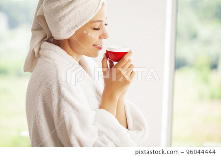 Studio shot of beautiful young woman applying moisturizer cream onto her face Studio shot of beautiful young woman applying moisturizer cream onto her face 96044444