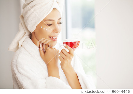 Perfect young woman applying facial cream in bathroom Perfect young woman applying facial cream in bathroom 96044446