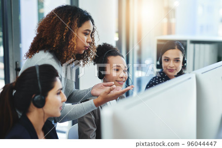 Customer satisfaction is a team effort in our department. Shot of a young woman assisting her colleagues in a call centre. 96044447