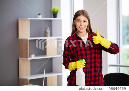 A young female professional cleaner cleans a modern office A young female professional cleaner cleans a modern office 96044669