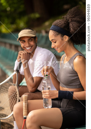 Two tennis players resting after the game and looking contented Two tennis players resting after the game and looking contented 96044689
