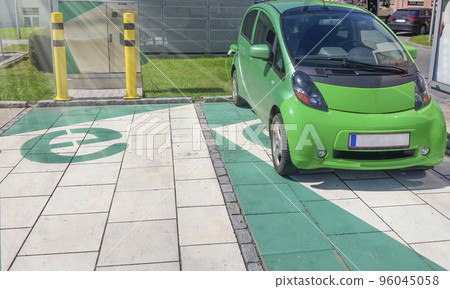 Modern electric car plugged in, charging on the street station. New energy vehicles, environment friendly alternative energy for cars Modern electric car plugged in, charging on the street station. New energy vehicles, environment friendly alternative energy for cars 96045058