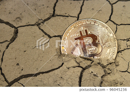 bitcoin in the form of a coin lies on dry cracked ground 96045236