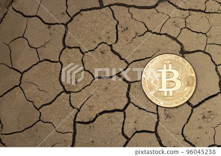 Golden bitcoin in the form of a coin lies on dry ground 96045238