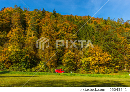 Small red car passing through beautiful autumn landscape near Graz, Styria region, Austria 96045341