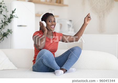 Favorite Pastime. Cheerful Black Woman Listening Music In Wireless Headphones At Home Favorite Pastime. Cheerful Black Woman Listening Music In Wireless Headphones At Home 96045344