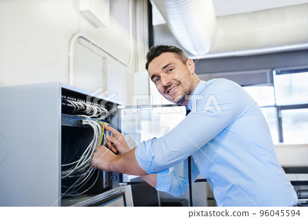 Youll be online in one more minute. Portrait of a smiling computer engineer working on a server. Youll be online in one more minute. Portrait of a smiling computer engineer working on a server. 96045594