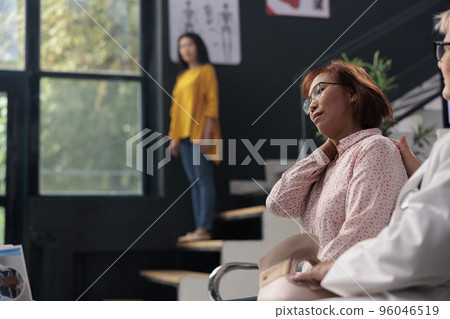 Asian woman removing neck collar with physician and nurse, receiving help from medical staff. Patient wearing cervical brace to recover after accident injury, doing checkup at health clinic 96046519