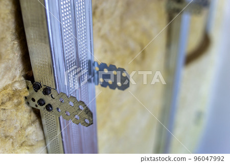 Wall of a room under renovation with mineral rock wool insulation and metal frame prepared for drywall plates. 96047992