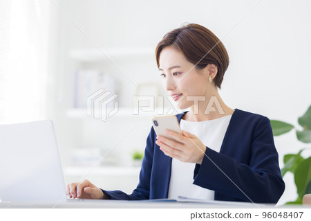 Business portrait of a woman looking at a smartphone Business portrait of a woman looking at a smartphone 96048407