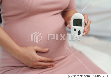 pregnant woman holding glucose meter with result of measurement sugar high level. gestational diabetes concept. 96051231
