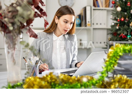 Businesswoman doing her daily work in office during Christmastime Businesswoman doing her daily work in office during Christmastime 96052307