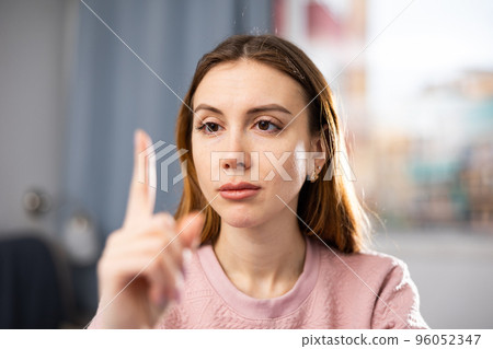 Girl checks her eyesight - carefully looks at her finger. Gymnastics for eyes 96052347