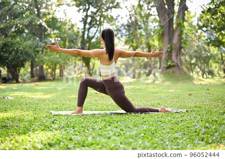 Active Asian woman training in the green park, doing Crescent Lunge Twist on the knee pose Active Asian woman training in the green park, doing Crescent Lunge Twist on the knee pose 96052444