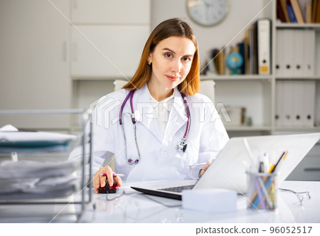 Focused woman doctor working in medical office using laptop Focused woman doctor working in medical office using laptop 96052517