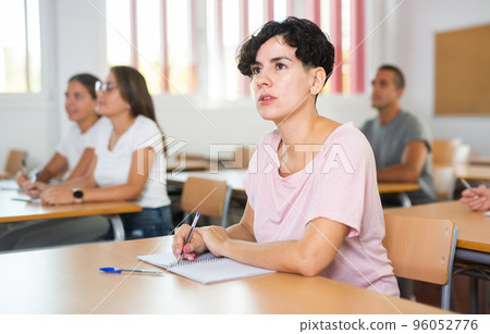 Focused young Chilean woman listening and making notes of lecture 96052776