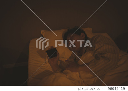 A man in his 40s sleeping with a bedroom and a smartphone A man in his 40s sleeping with a bedroom and a smartphone 96054419