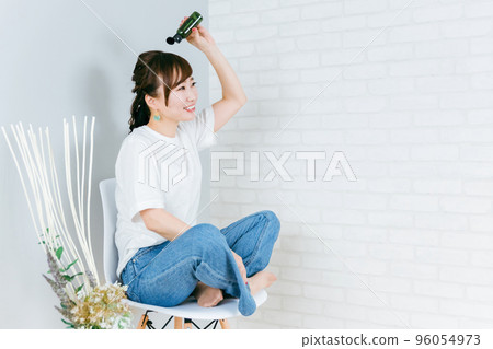Japanese woman applying hair care products and styling products to her hair 96054973