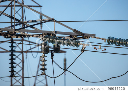 Insulators of high voltage overhead power lines are under blue sky 96055220