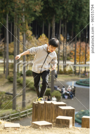 Elementary school boy playing in the park while balancing Elementary school boy playing in the park while balancing 96055794