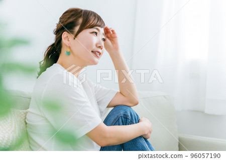 一位微笑的日本女性在家裡放鬆和在沙發上放鬆時感到快樂的簡介 96057190