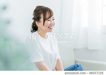 一位微笑的日本女性在家裡放鬆和在沙發上放鬆時感到快樂的簡介 96057195