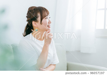 Profile of smiling Japanese woman thinking while relaxing at home and relaxing on sofa 96057197