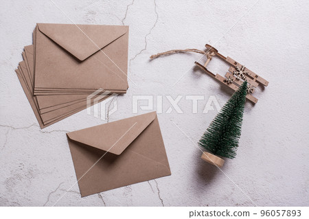 Empty craft envelopes, a Christmas tree and a wooden sledge on plaster. Top view. Empty craft envelopes, a Christmas tree and a wooden sledge on plaster. Top view. 96057893