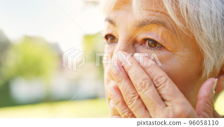 She gets teary when she misses her loved one. Closeup shot of a sad senior woman wiping tears off her face outdoors. She gets teary when she misses her loved one. Closeup shot of a sad senior woman wiping tears off her face outdoors. 96058110
