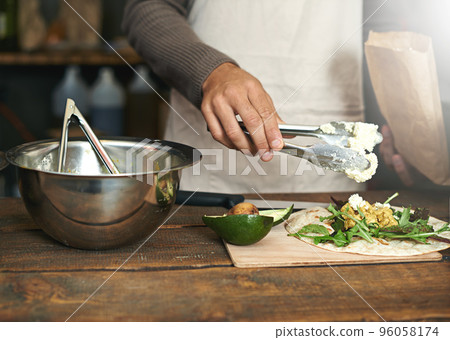 Making good food from fresh ingredients. Cropped shot of a man preparing a meal in a kitchen. 96058174
