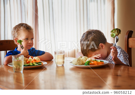 Thats it, were going on a hunger strike. Shot of two unhappy little boys refusing to eat their vegetables at the dinner table. 96058212