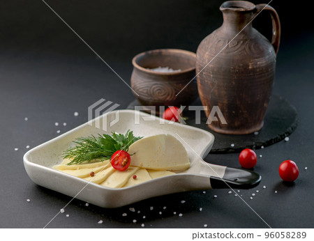 homemade organic white cheese with tomatoes and greens in a plate on a dark background 96058289