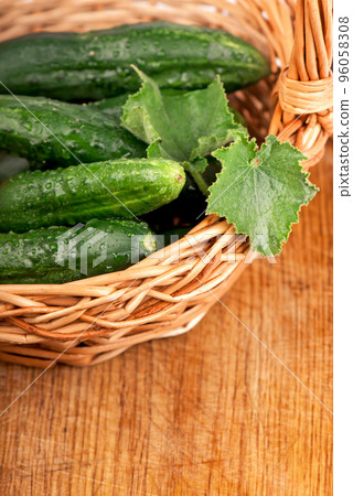 fresh cucumbers with green leaves in a basketon wooden background fresh cucumbers with green leaves in a basketon wooden background 96058308