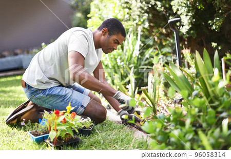 Rooting out the problem. Cropped shot of a handsome young man gardening. Rooting out the problem. Cropped shot of a handsome young man gardening. 96058314