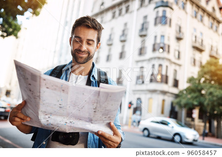 Im exactly where I want to be. Cropped shot of a handsome young man looking at a map while touring a foreign city. Im exactly where I want to be. Cropped shot of a handsome young man looking at a map while touring a foreign city. 96058457