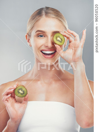 Happy studio portrait, woman with kiwi for skincare wellness, health and beauty by grey wall. Cosmetics model, girl with smile, fruit and self care for healthy facial, skin or vitamins by background Happy studio portrait, woman with kiwi for skincare wellness, health and beauty by grey wall. Cosmetics model, girl with smile, fruit and self care for healthy facial, skin or vitamins by background 96058520