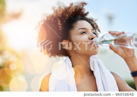 Maintaining good hydration also supports healthy weight loss. Cropped shot of a young woman enjoying a bottle of water while out for a run. 96058648