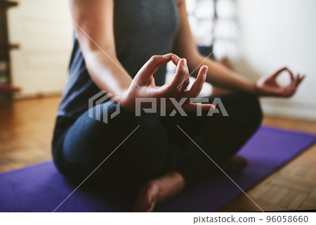 Finding my balance. Cropped shot of an unrecognizable woman sitting on a yoga mat and meditating alone in her home. Finding my balance. Cropped shot of an unrecognizable woman sitting on a yoga mat and meditating alone in her home. 96058660