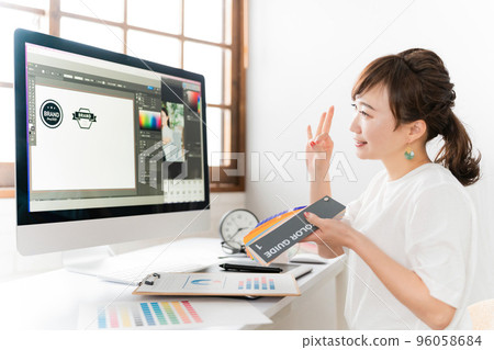 A designer Asian woman who has an online meeting / web conference while looking at the color sample 96058684