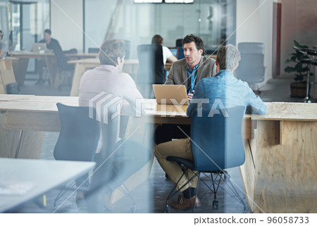 Getting straight to the point. Through the glass shot of a group of colleagues working together in an office. Getting straight to the point. Through the glass shot of a group of colleagues working together in an office. 96058733