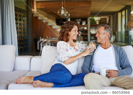 And then I said.... A happy mature couple enjoying a cup of coffee together on the sofa at home. 96058966