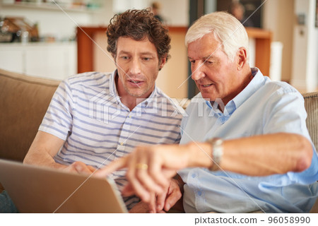 Explain that part to me again.... Shot of a man and his father sitting with a laptop indoors. 96058990