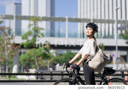 一位女商人肩上背著背包走路,從旁邊拉著一輛公路自行車 一位女商人肩上背著背包走路,從旁邊拉著一輛公路自行車 96059015